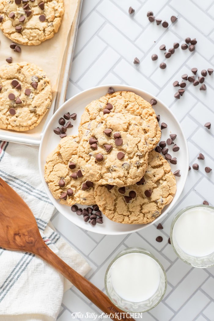 A plate of homemade chocolate chip cookies with a glass of milk and scattered mini chips.
