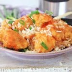 Instant Pot sweet and sour chicken served over white rice in a bowl with green onions.