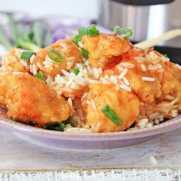 Instant Pot sweet and sour chicken served over white rice in a bowl with green onions.