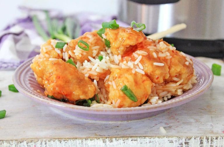 Instant Pot sweet and sour chicken served over white rice in a bowl with green onions.