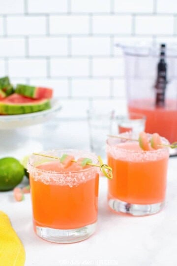 Two watermelon vodka slush cocktails in sugar-rimmed glasses with lime.