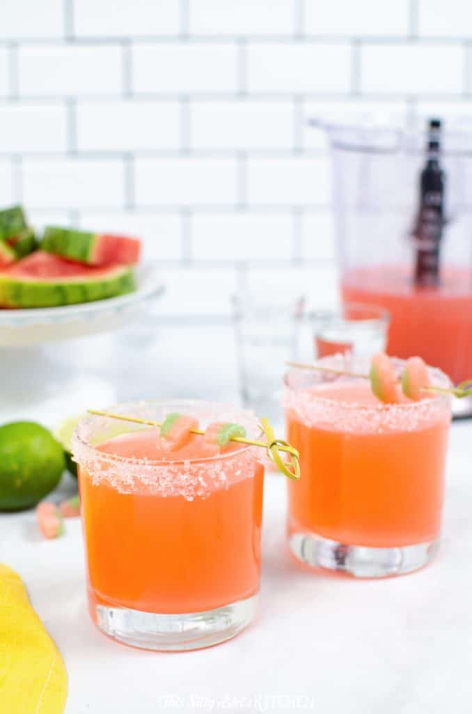 Two watermelon vodka slush cocktails in sugar-rimmed glasses with lime.