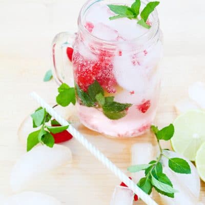 Raspberry mojito in a mason jar mug with crushed raspberries, fresh mint, and lime by the pool.