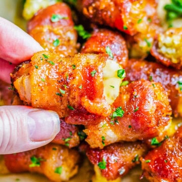 Square image close up of Bacon Bombs with hand holding one.