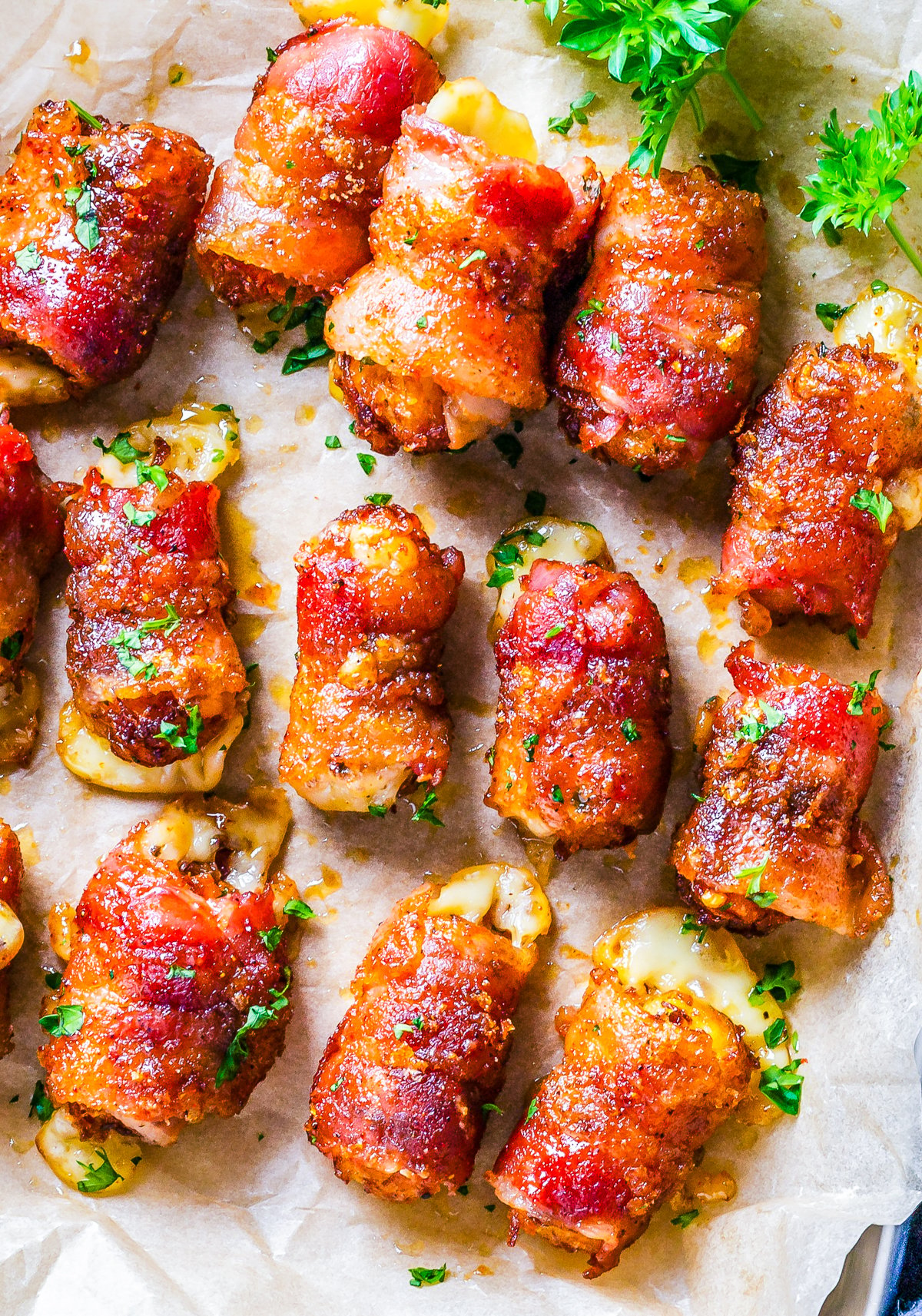Finished Sweet & Spicy Bacon Bombs overhead on parchment lined tray with parsley.