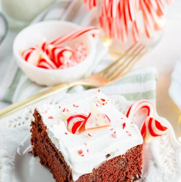 One slice of cake on white plate with candy canes in background