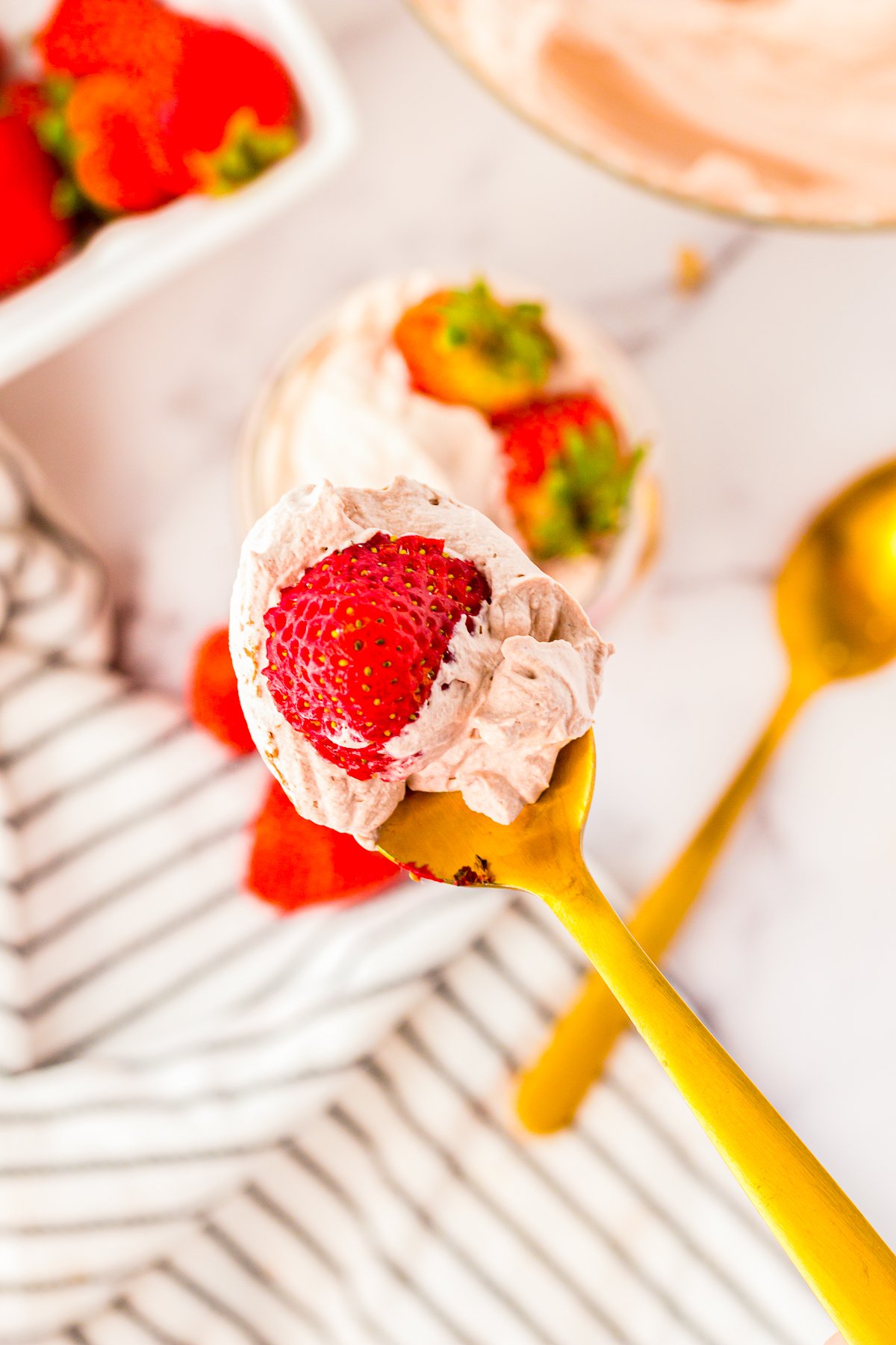 Spoon full of Chocolate Whipped Cream on gold spoon with strawberries.
