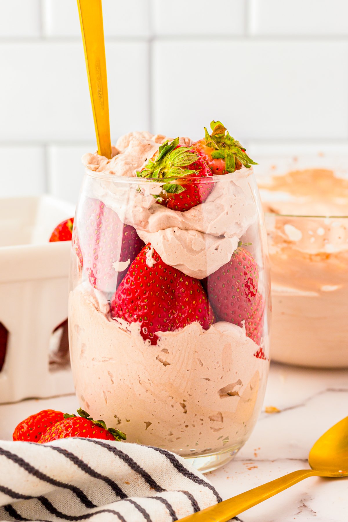 Chocolate Whipped Cream in glass with strawberries and golden spoon.