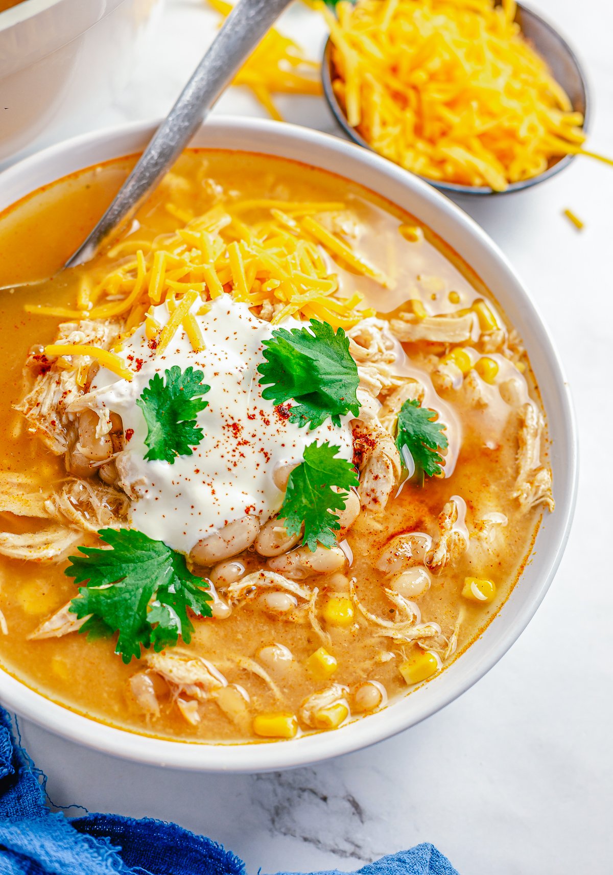 Easy White Chicken Chili in white bowl with spoon, garnished.