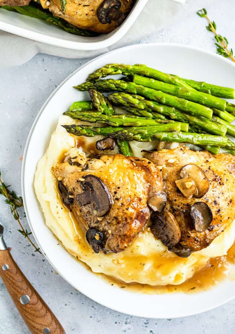 Slow cooker chicken marsala served over mashed potatoes with asparagus and mushrooms.
