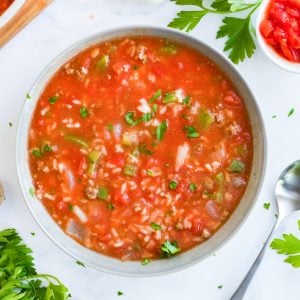 An overhead bowl of stuffed pepper soup with ground beef, rice, peppers, and tomatoes, garnished with parsley.