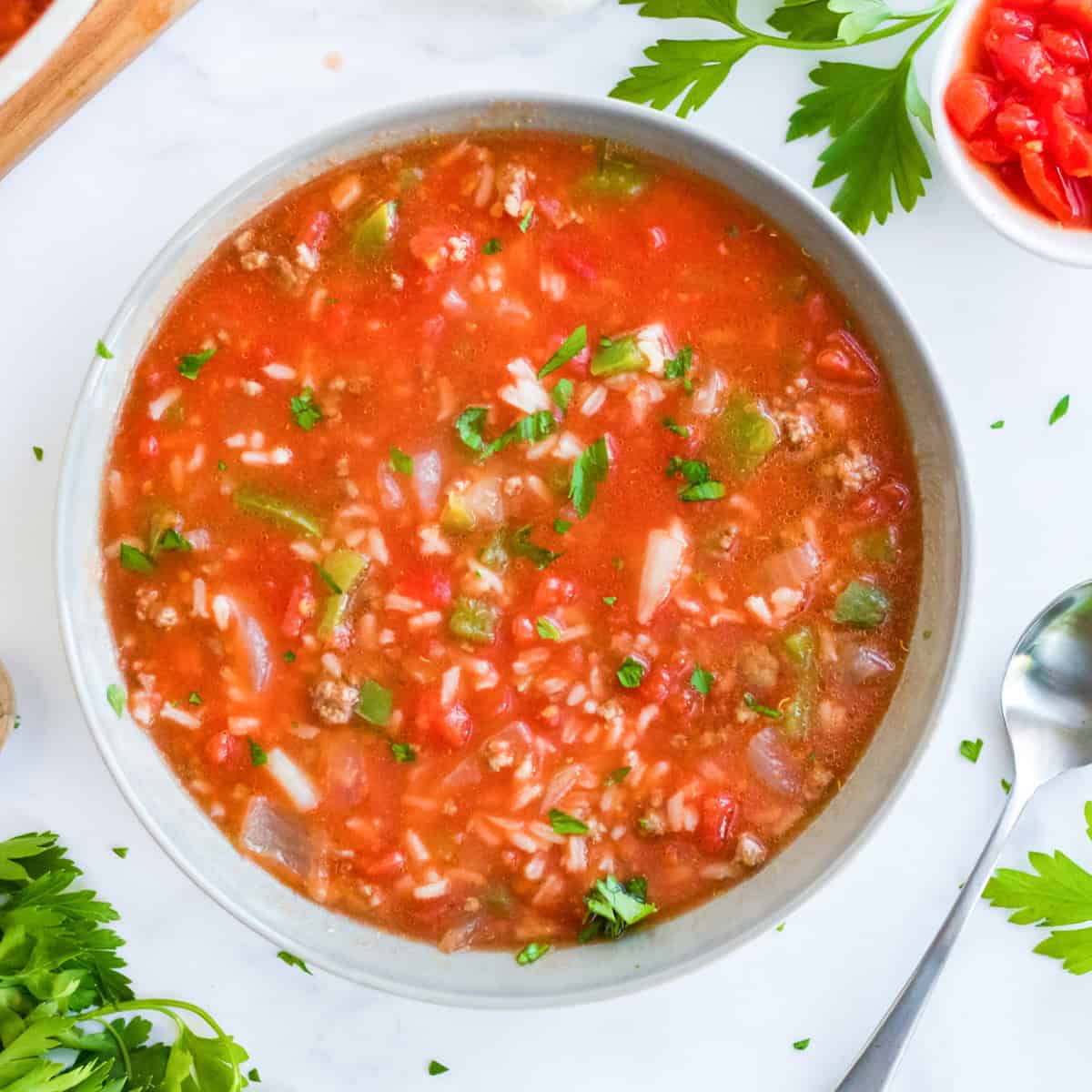 An overhead bowl of stuffed pepper soup with ground beef, rice, peppers, and tomatoes, garnished with parsley.