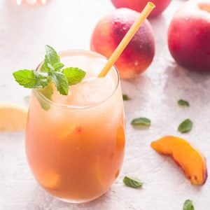 Close up of drink in glass with straw and peaches