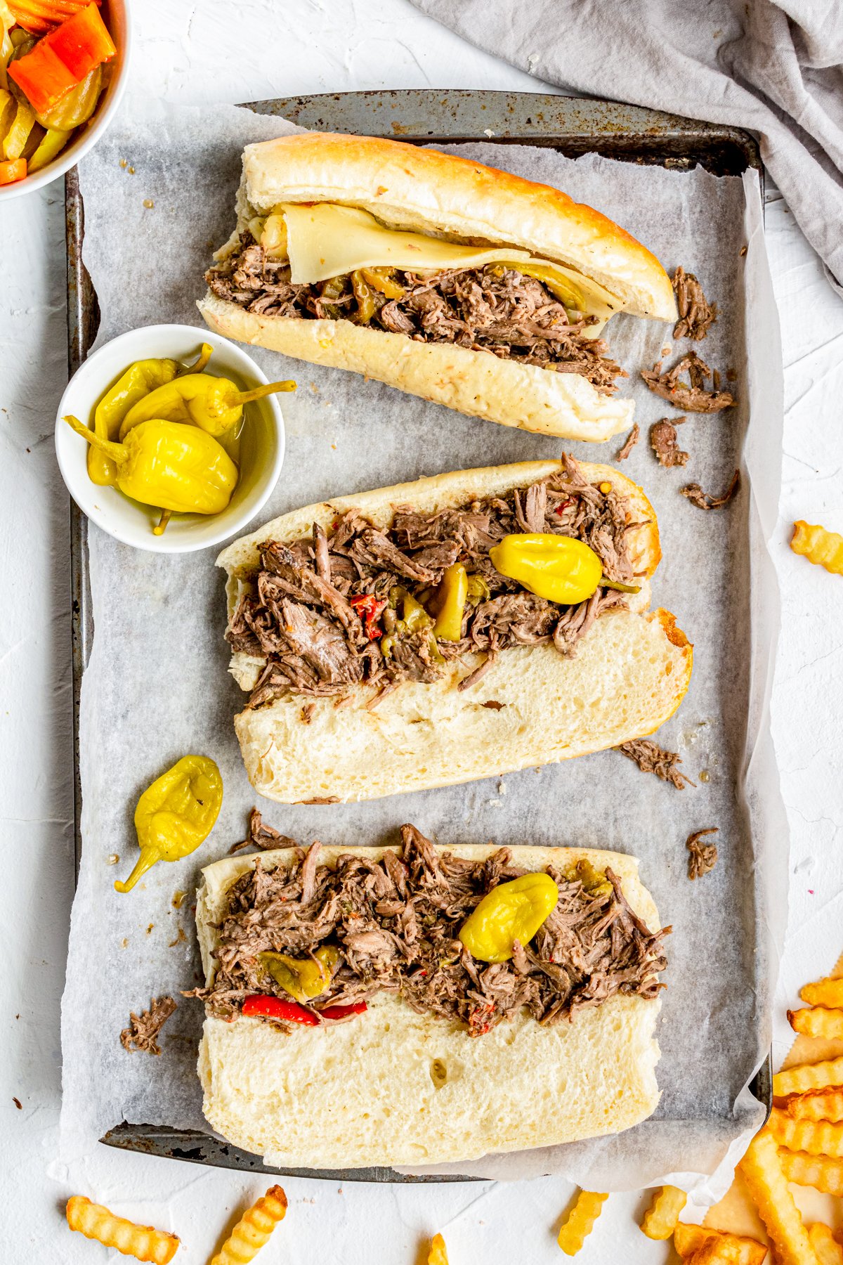Italian Beef Sandwiches on tray open with pepperocinis on top and in bowl