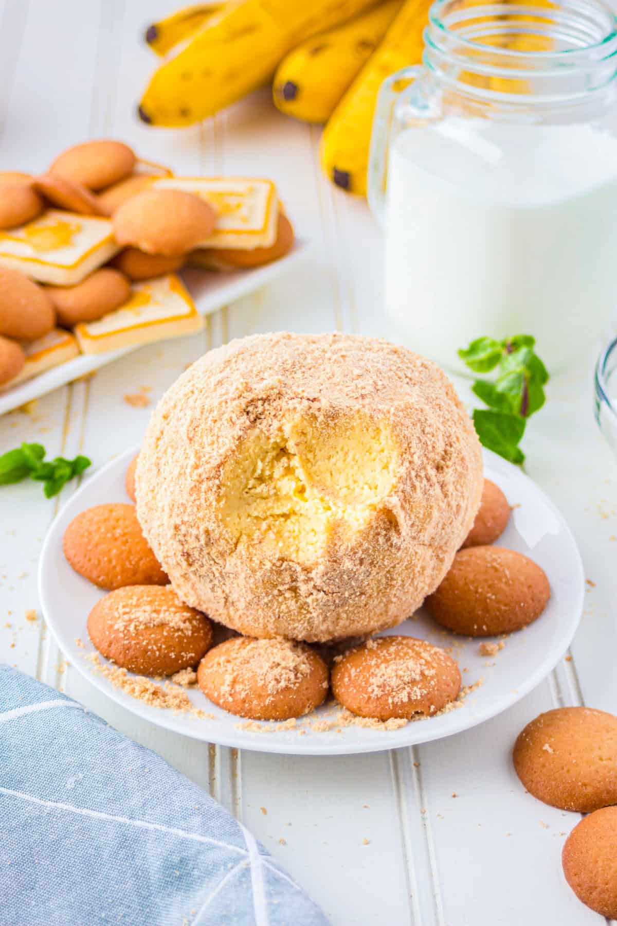 Banana pudding cheese ball with a scoop taken out showing the creamy filling inside.