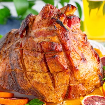 A whole copycat honey baked ham with a sticky golden glaze on a platter.