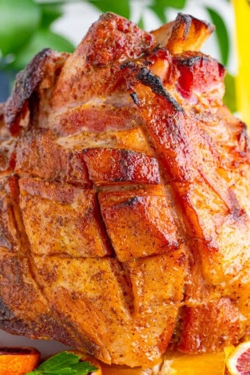A whole copycat honey baked ham with a sticky golden glaze on a platter.