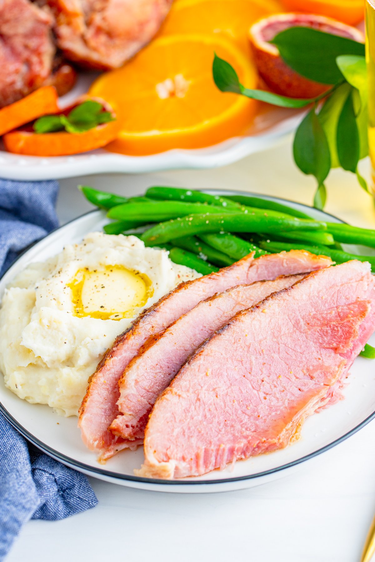 Sliced Honey Baked Ham on plate with mashed potatoes and green beans
