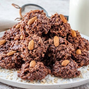 Stacked no bake almond joy cookies on a platter each topped with a whole almond