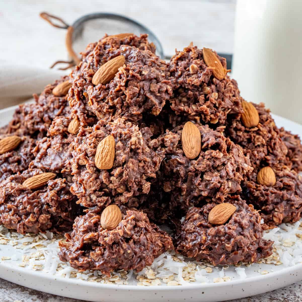 Stacked no bake almond joy cookies on a platter each topped with a whole almond