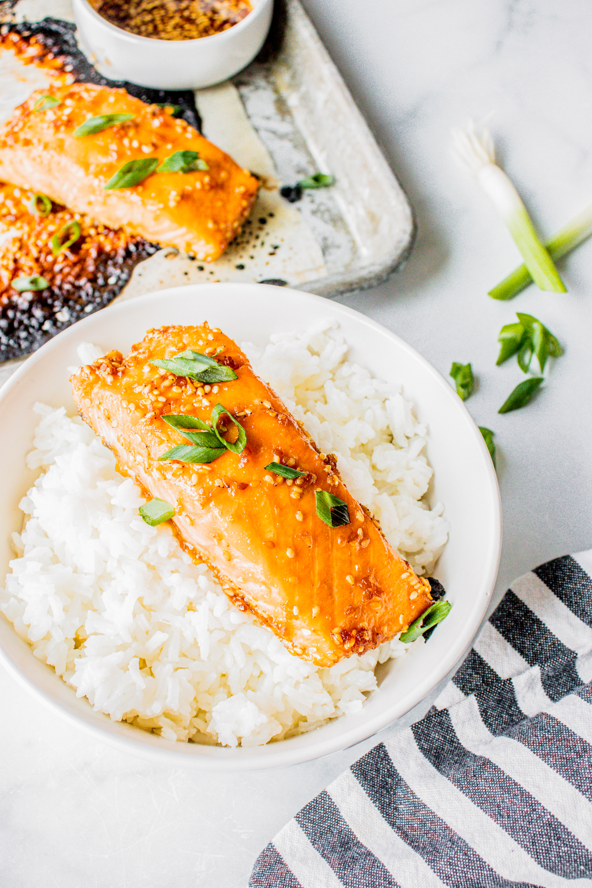 Side view of Teriyaki Salmon Recipe over rice with more salmon on pan