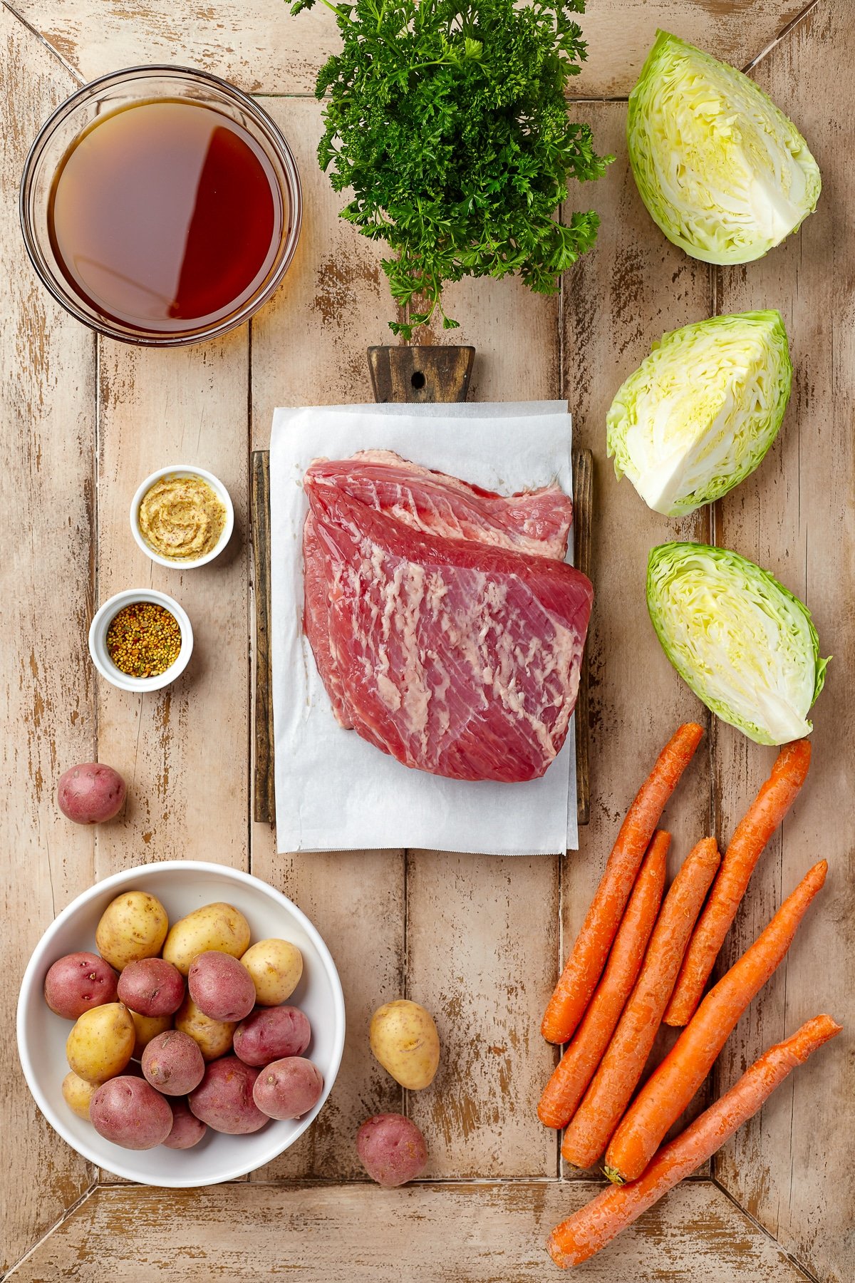 Over head shot of all the ingredients needed to make Slow Cooker Corned beef and cabbage on a wooden background