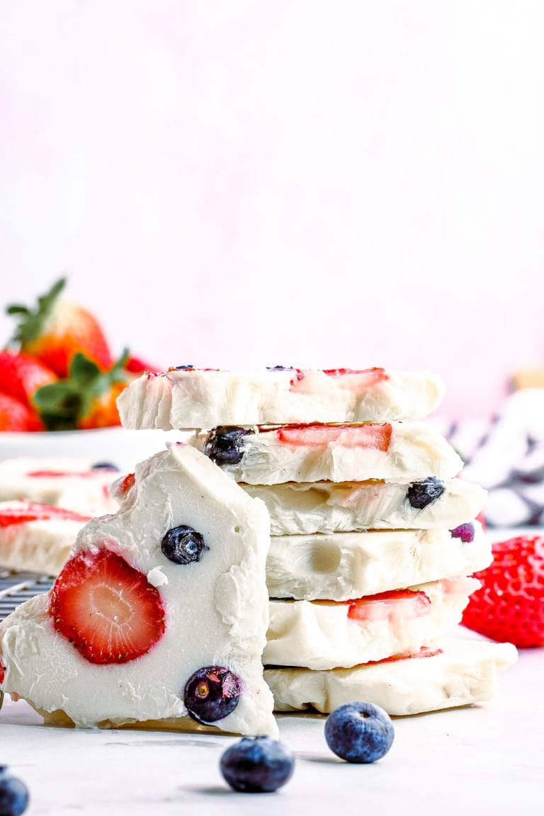 A stack of frozen Yogurt Bark pieces studded with strawberry slices and blueberries.