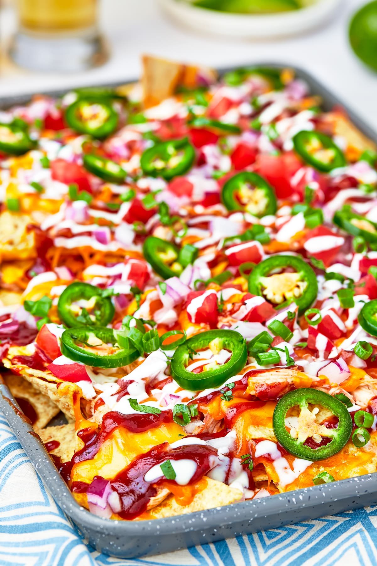 45 degree angle of BBQ Chicken Nachos on a sheet tray with lots of yummy toppings