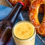 A jar of creamy beer cheese dip served with soft pretzels.