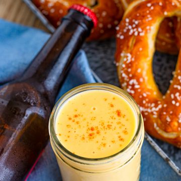 A jar of creamy beer cheese dip served with soft pretzels.