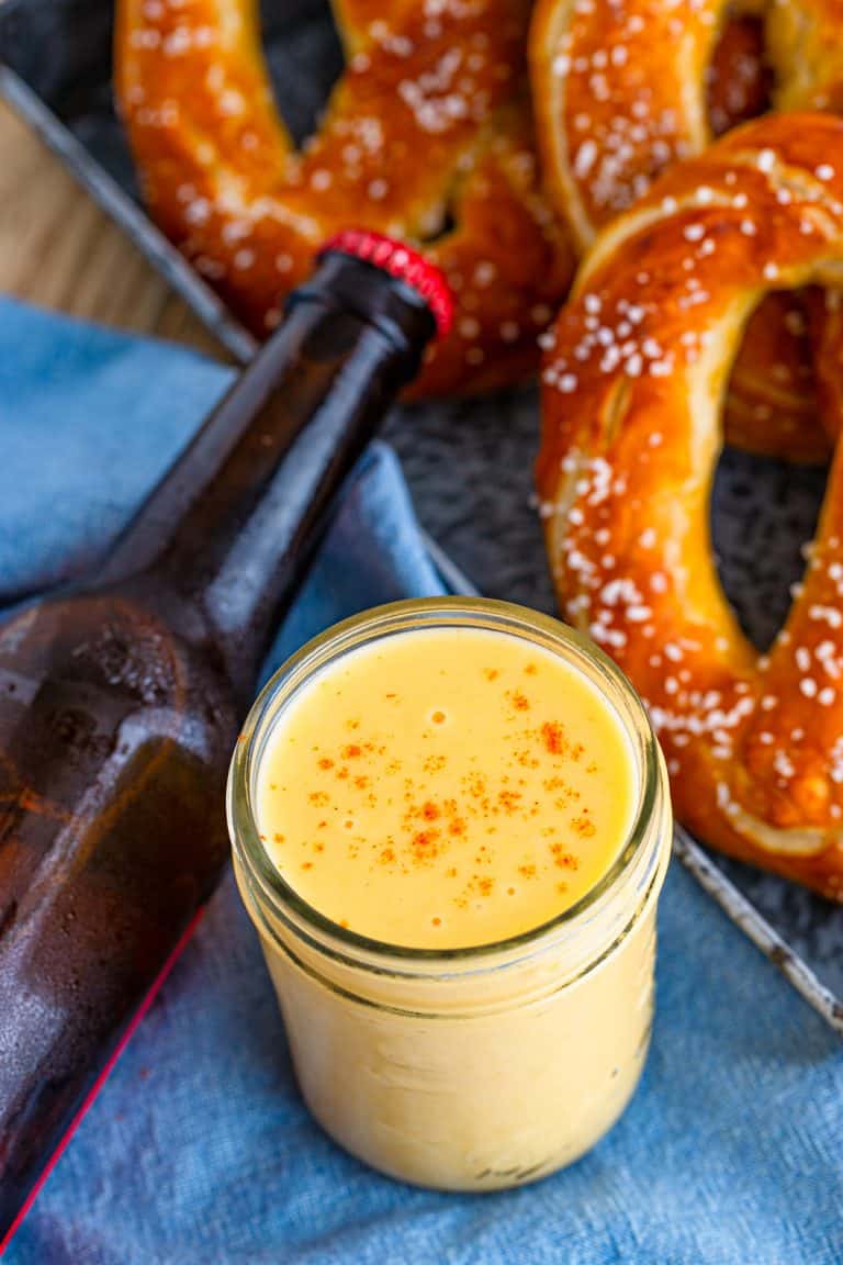 A jar of creamy beer cheese dip served with soft pretzels.