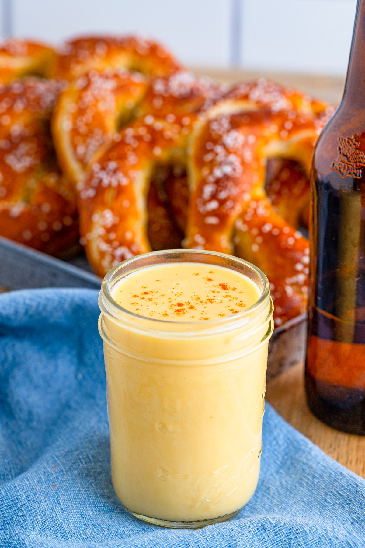 Jar filled with Creamy Beer Cheese Dip with pretzels in background