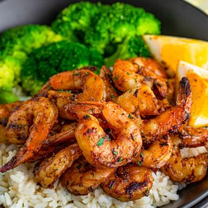 Close up square image of Blackened Shrimp over rice with vegetables