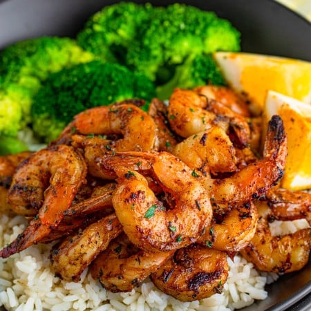 Close up square image of Blackened Shrimp over rice with vegetables