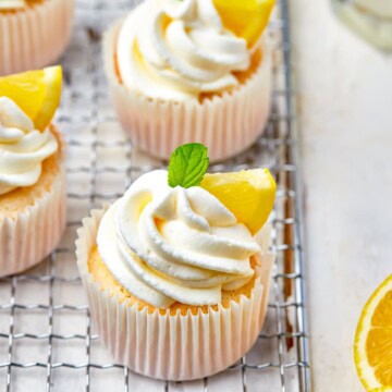 Lemon angel food cupcakes topped with swirled whipped cream and yellow sprinkles.