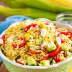 A bowl of orzo pasta salad with tomatoes, cucumber, corn, and feta
