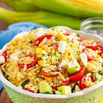 A bowl of orzo pasta salad with tomatoes, cucumber, corn, and feta