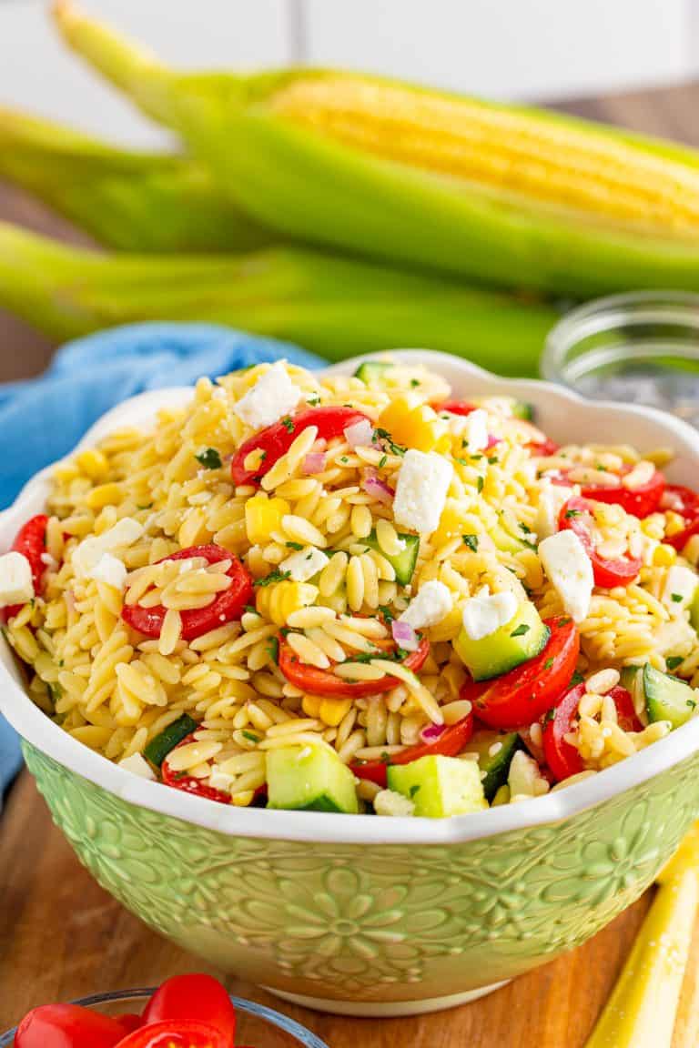 A bowl of orzo pasta salad with tomatoes, cucumber, corn, and feta