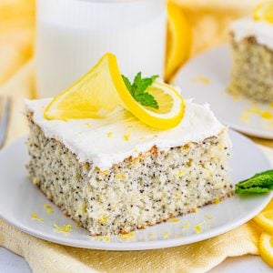 Square photo of slice of cake on white plate topped with lemon and mint