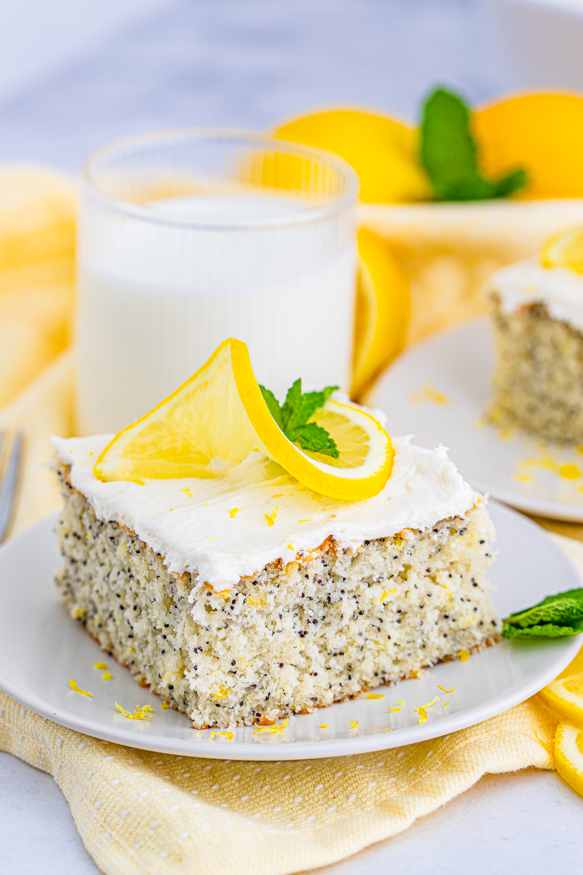 Lemon Poppy Seed Cake slice on white plate topped with lemon and mint