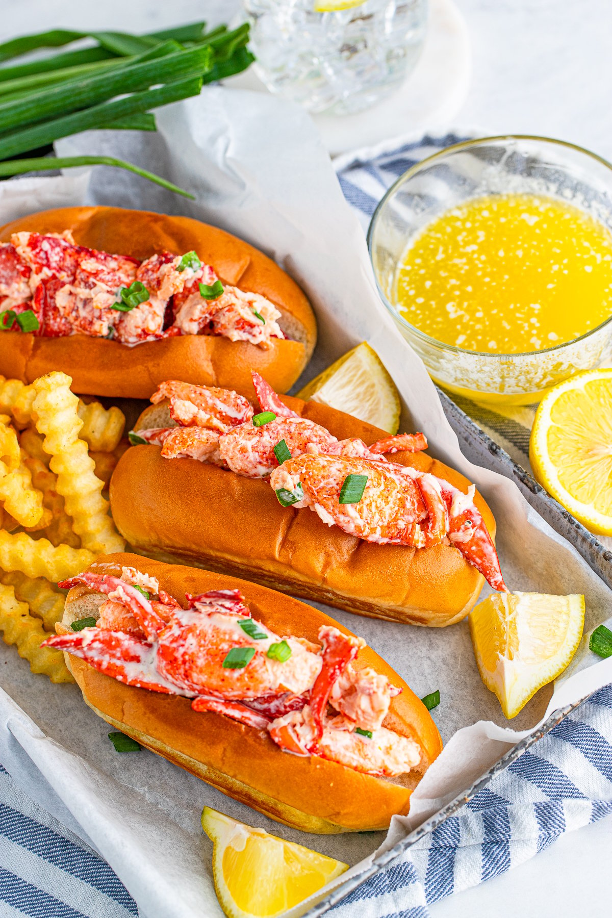 Lobster Roll Recipe on tray with lemons, French fries and butter
