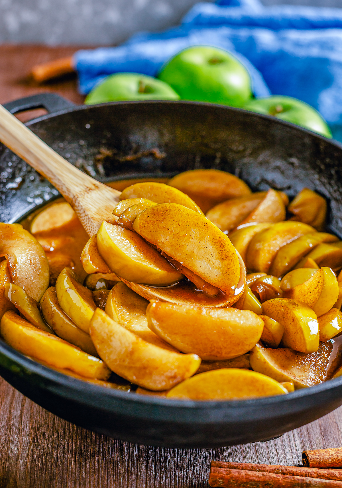 Fried Apples in skillet with wooden spoon.