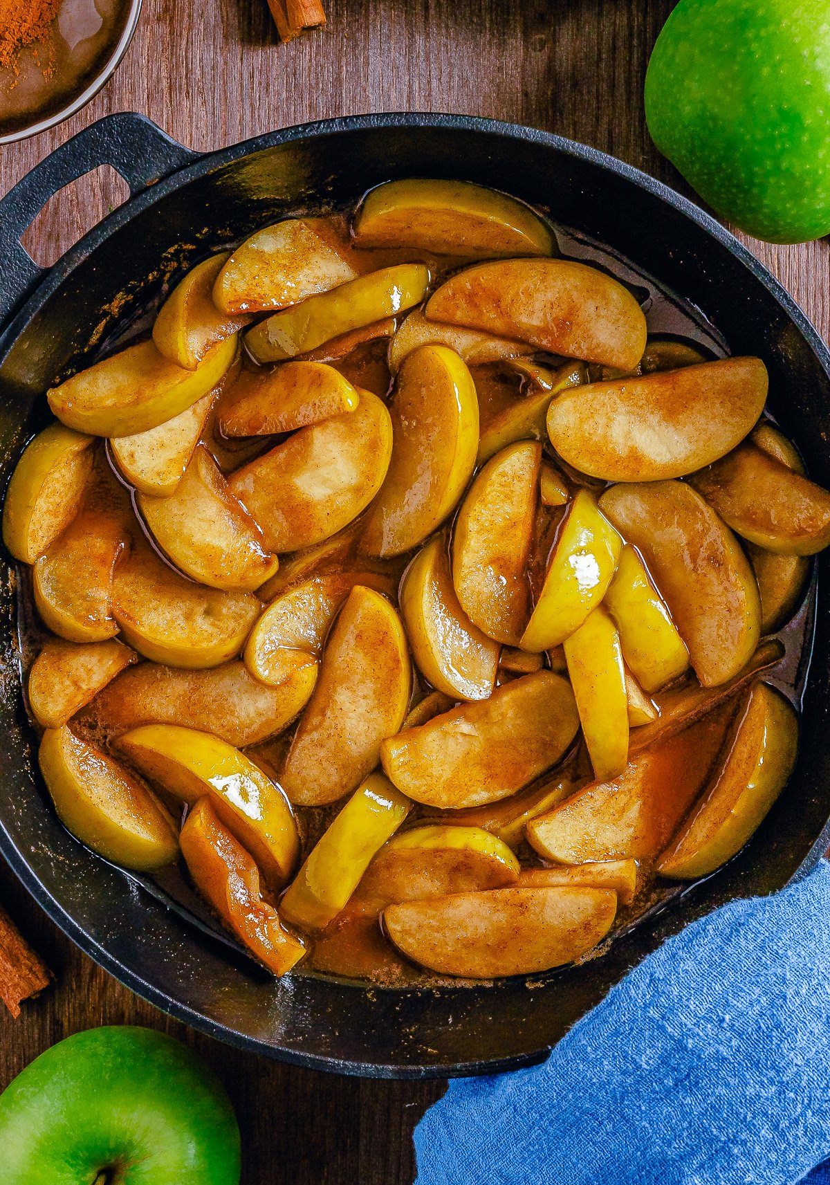 Overhead photo of Fried Apples in cast iron skillet with apples on sides.