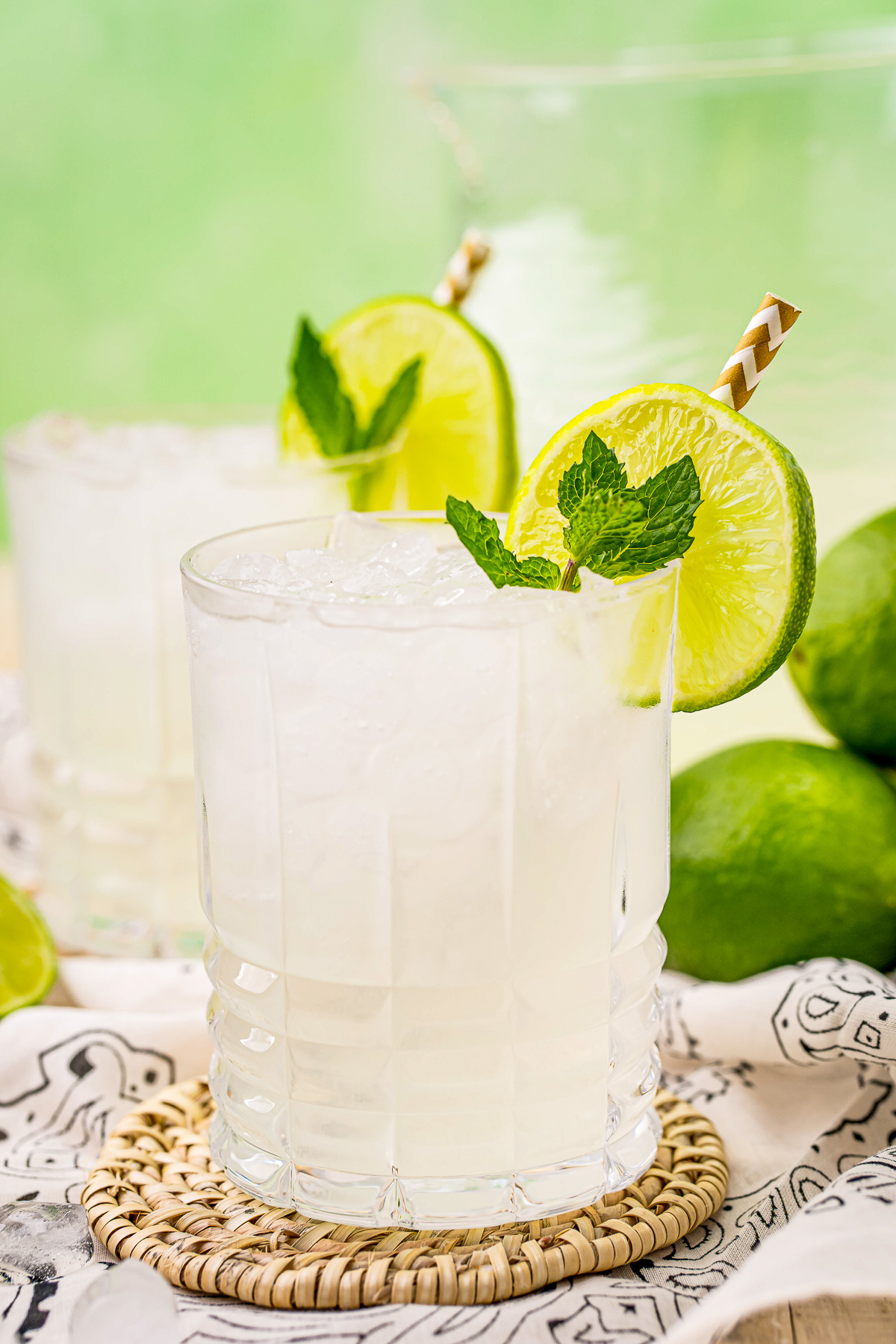 Close up of one glass of the Limeade Recipe garnished with straw, mint and limes