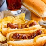 Slow cooker beer brats piled on a bun and topped with caramelized onions.