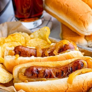 Slow cooker beer brats piled on a bun and topped with caramelized onions.