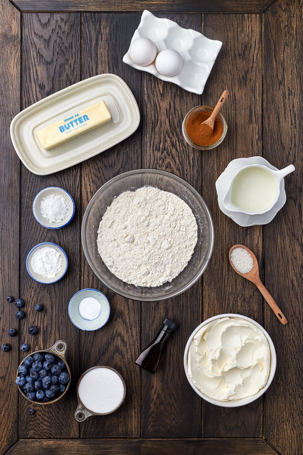 Overhead shot of ingredients needed to make blueberry cream cheese muffins on a dark wooden tabletop