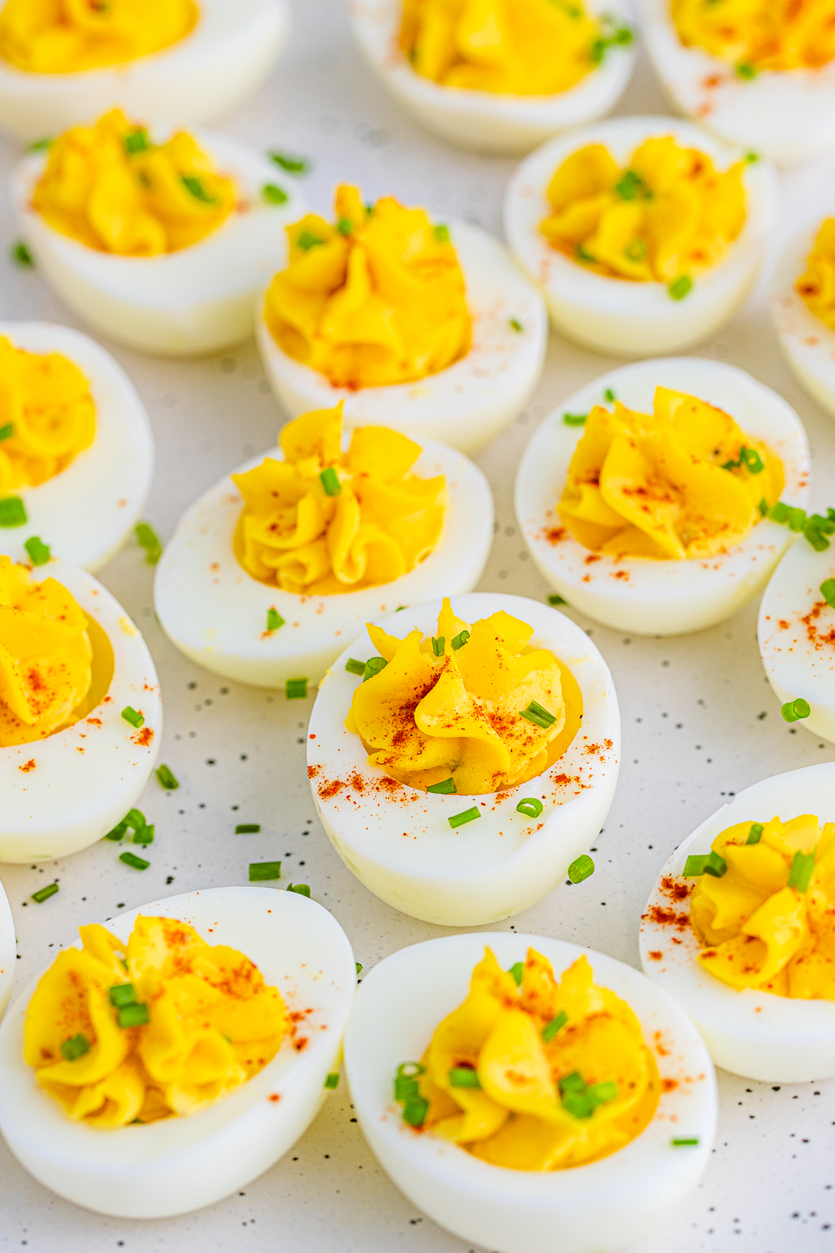 Close up of garnished eggs on white platter.