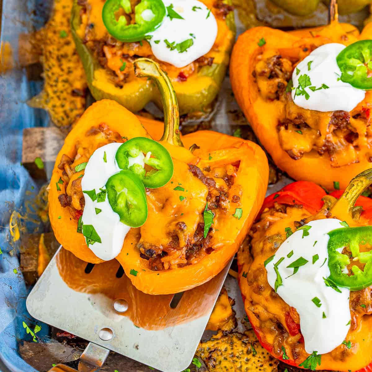 A Mexican stuffed pepper half loaded with beef and rice, topped with melted cheese, sour cream, and jalapeno on a plate.