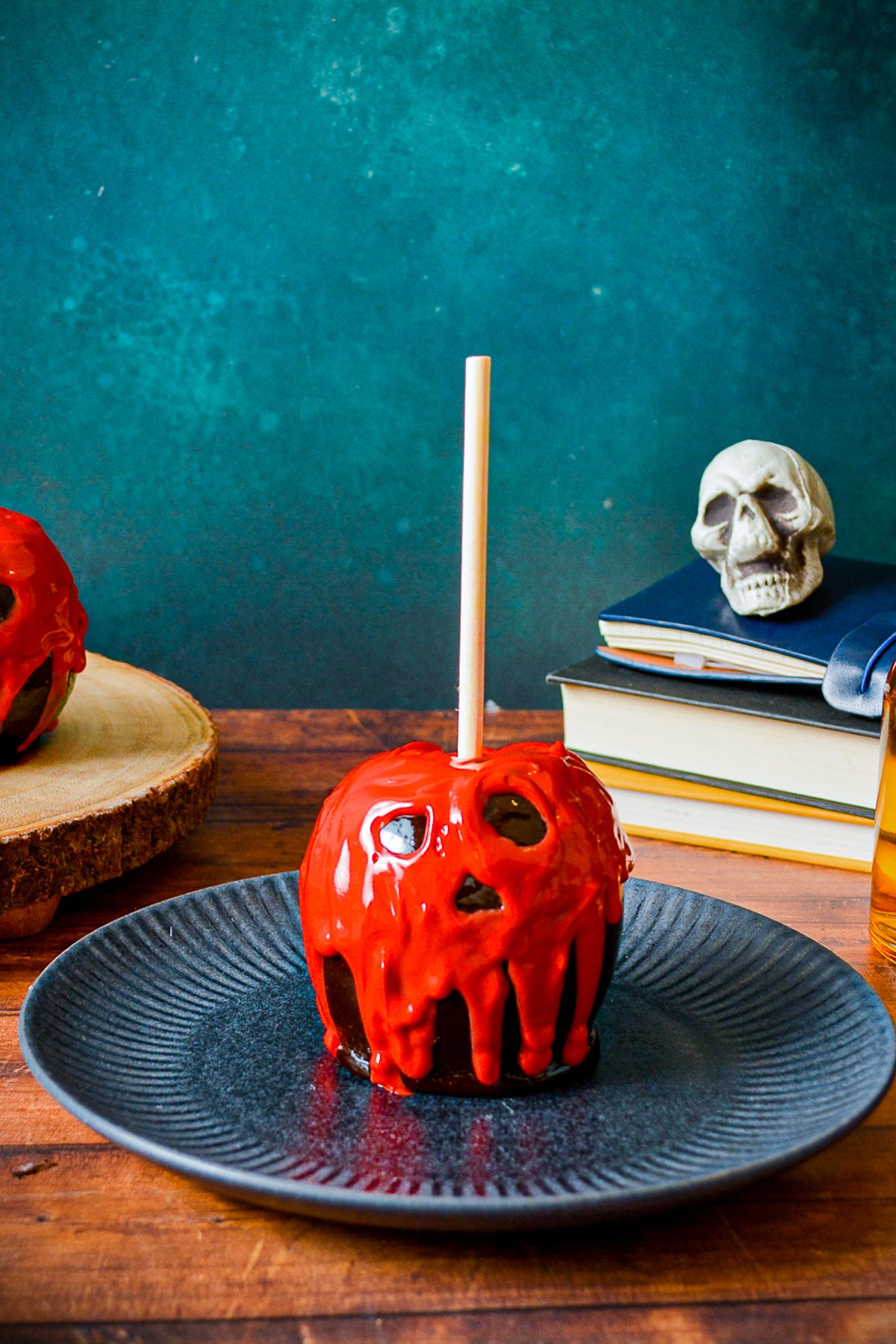 One Poison Apple on plate with books and skull in background.